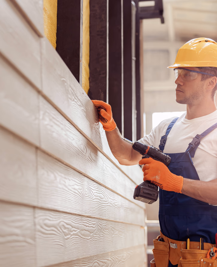 man holding a drill and examining a building